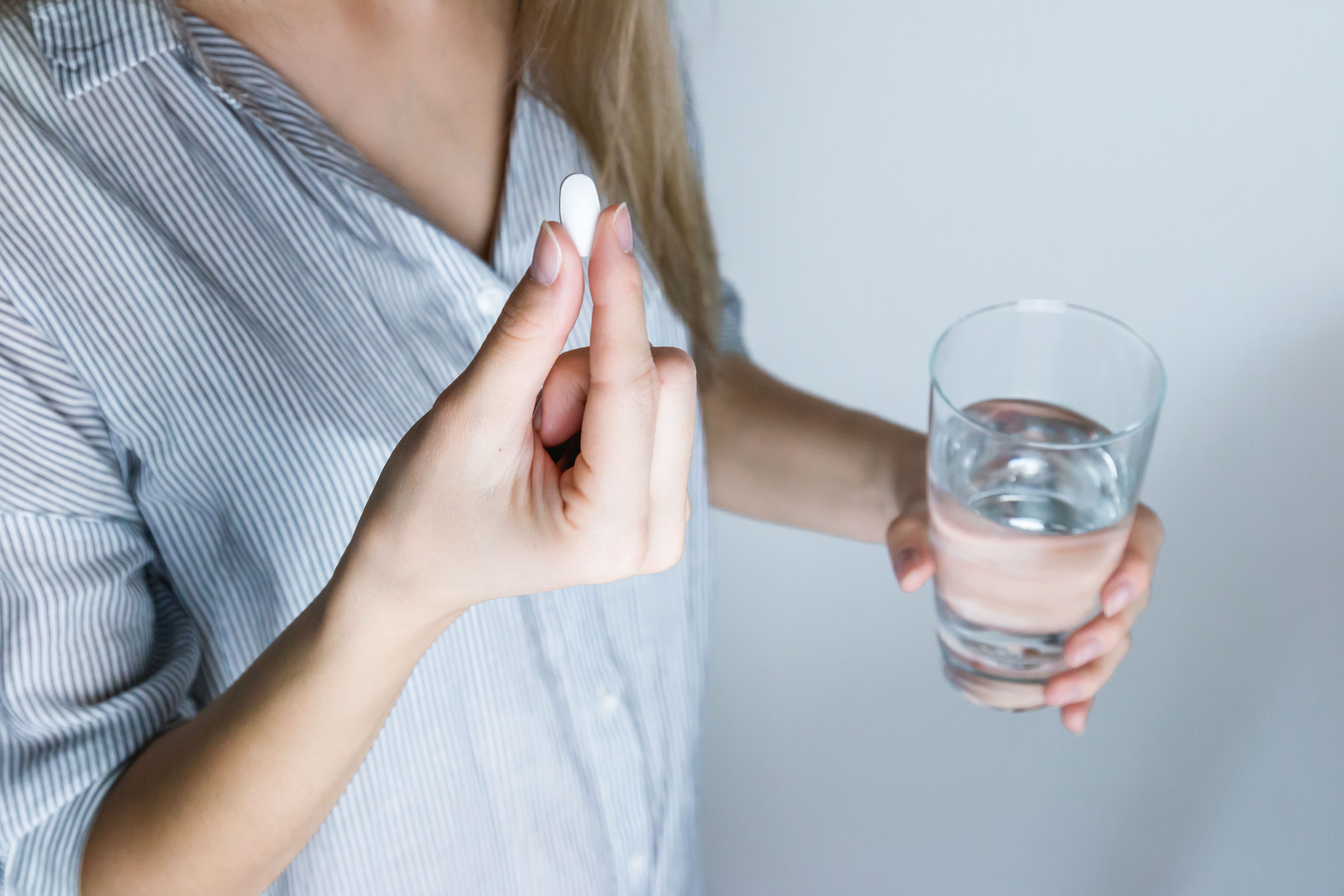 Image of a woman holding a glass of water and medicine