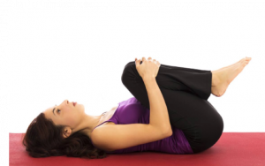 A woman demonstrating the knees to chest yoga pose that can help relieve menstrual cramps