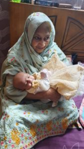 An image of Humaira Rizvi sitting on the floor cradling her infant grandchild