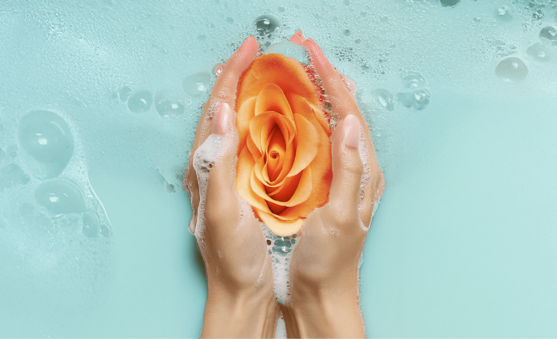 An image of 2 hands holding an orange flower with foam all around it