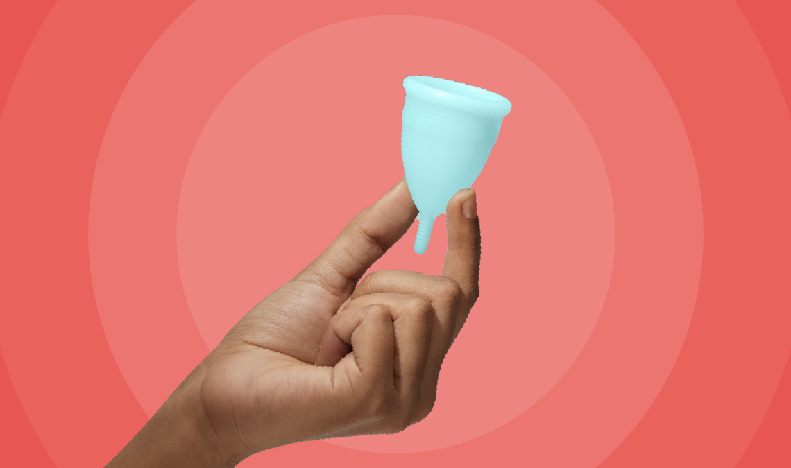 A hand holding a Nua menstrual cup