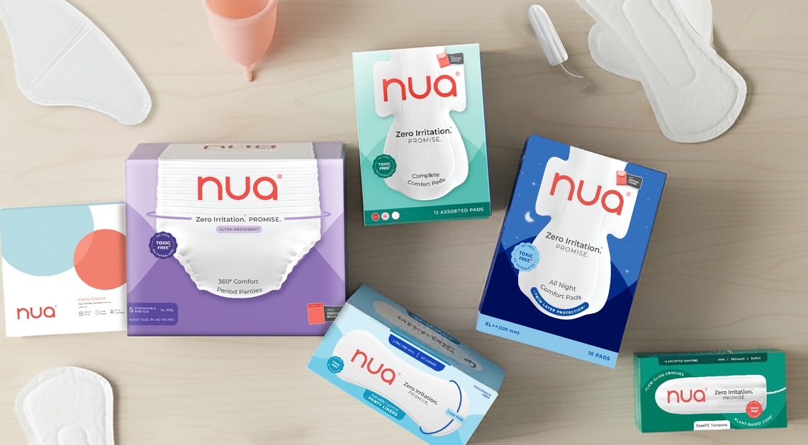 Flat lay of Nua period care products including pads, tampons, panty liners, and period panties displayed on a light wooden surface.