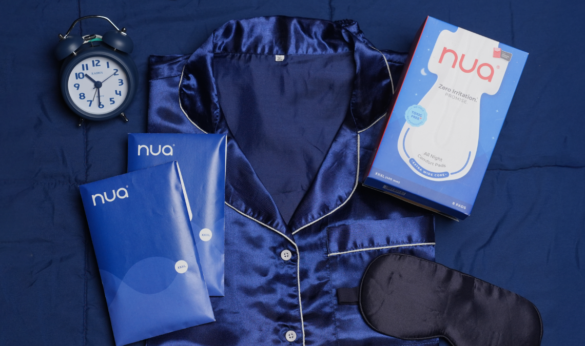 Flat lay of Nua all-night pads with packaging and sanitary pads arranged on a table, symbolizing comfort and protection during overnight periods.