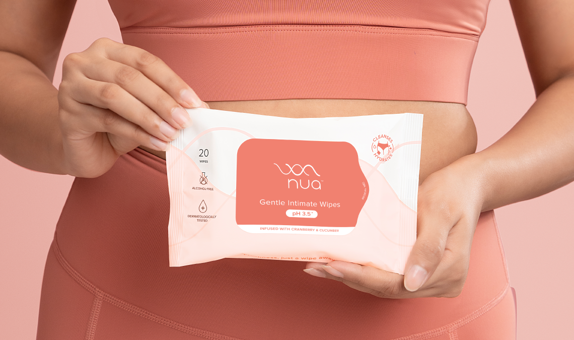 Woman holding Nua gentle intimate wipes in front of her midsection, showing pH-balanced wipes for safe and refreshing intimate hygiene.