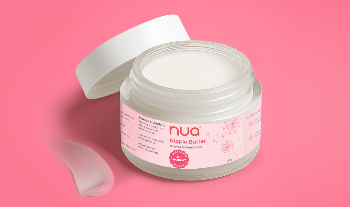 Open jar of Nua Nipple Butter on a pink background, with a small smear of cream beside it; label highlights coconut and calendula oil.
