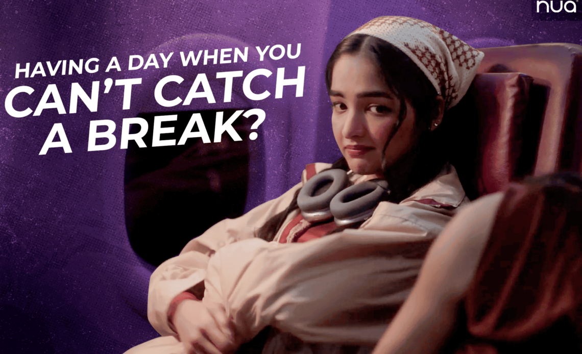 A woman sitting on a airplane wearing headphones, with text asking, “Having a day when you can’t catch a break?